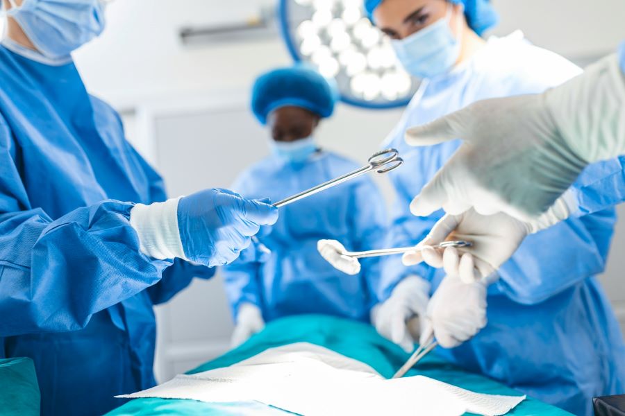 low angle shot in the operating room - assistant hands out instruments to surgeons during operation