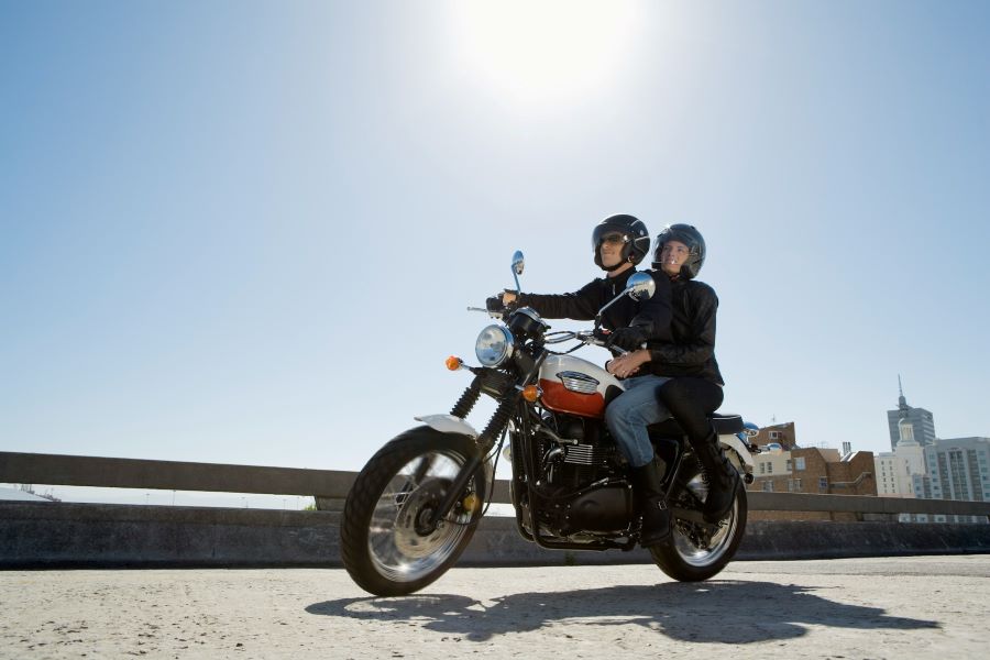 two people riding on a motorcycle with buildings in background