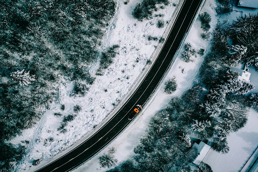 aerial image of a truck driving on a road surrounded by snow
