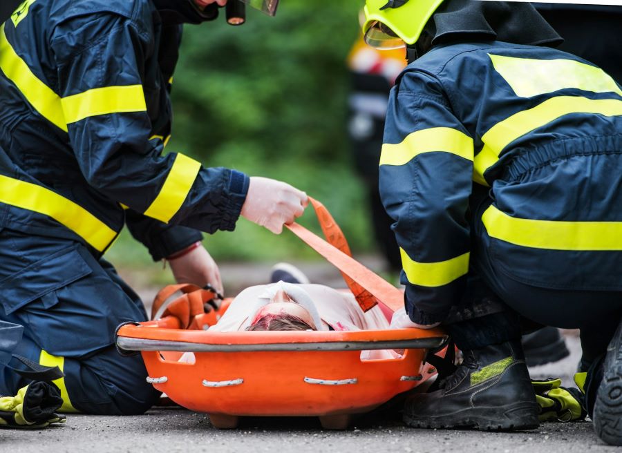 an injured woman lying on the ground on a stretcher while assisted by paramedics