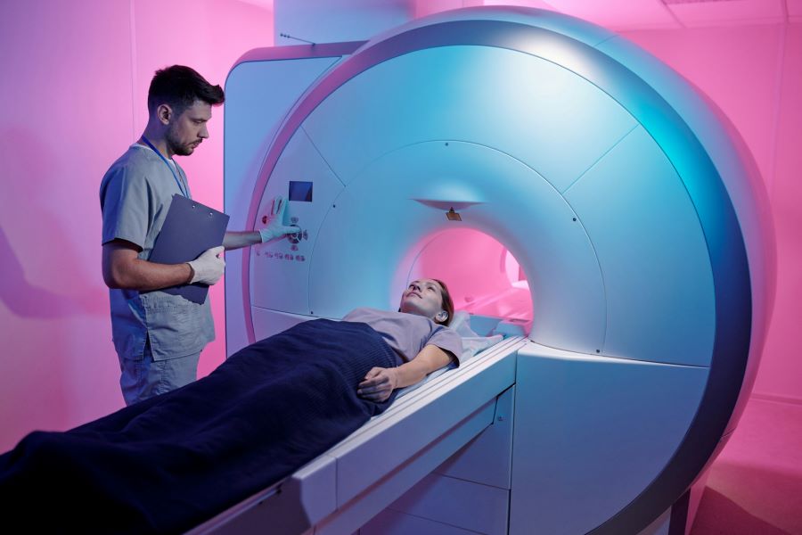 a woman lying in an mri bed with technician attending to her