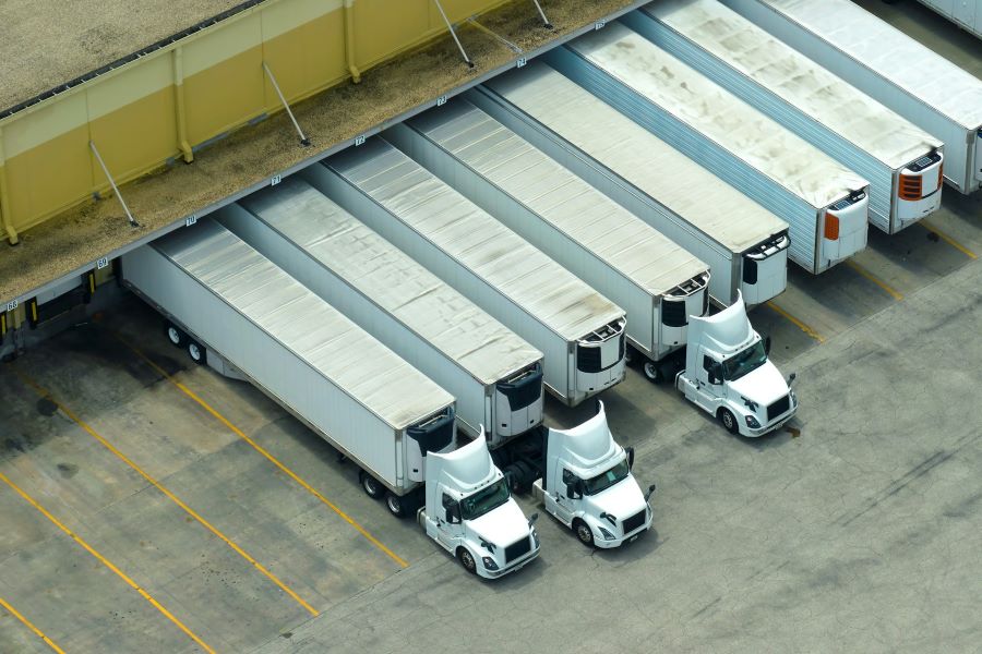 a row of semi trucks backed into a warehouse